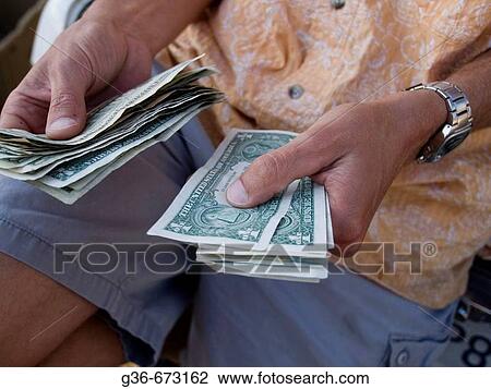 Stock Image - Merchant at farmer's market counts his change in Baywood Park, California. Fotosearch
