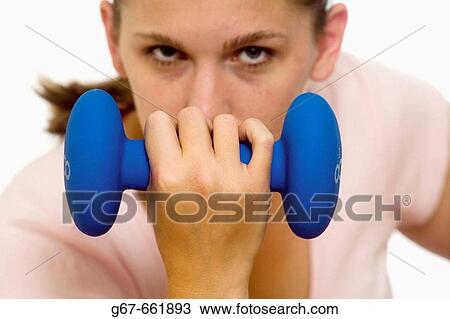 Mid 20's woman, background, de-focused, concentraits on exercising as she focuses on lifting an 8 pound weight View Large Photo Image Stock Image - Mid 20's woman, background, de-focused, concentraits on exercising as she focuses on lifting an 8 pound weight. Fotosearch