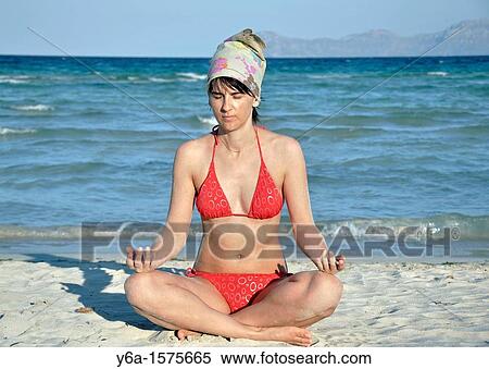 Stock Photography - Mid adult woman doing yoga on beach, Mallorca, Spain. Fotosearch