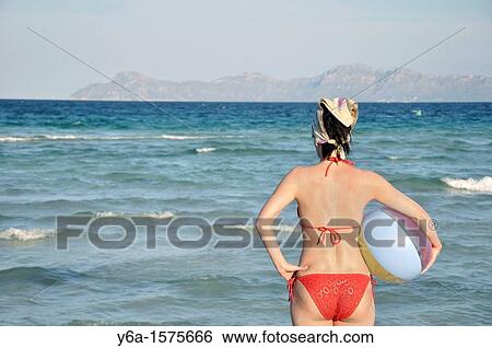 Mid adult woman holding beach ball on beach, rear view, Alcudia, Mallorca, Spain, Europe View Large Photo Image Stock Photograph - Mid adult woman holding beach ball on beach, rear view, Alcudia, Mallorca, Spain, Europe. Fotosearch