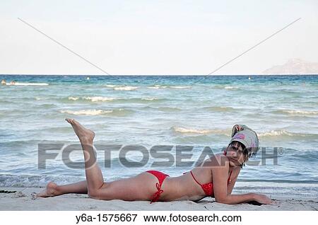 Mid adult woman lying on beach, Alcudia, Mallorca, Spain, Europe View Large Photo Image Stock Photo - Mid adult woman lying on beach, Alcudia, Mallorca, Spain, Europe. Fotosearch