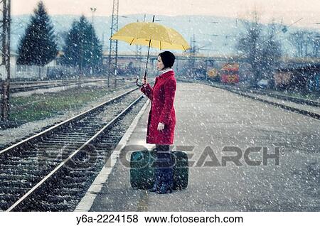 Mid adult woman standing on railroad station platform with suitcase holding umbrella. View Large Photo Image Stock Photo - Mid adult woman standing on railroad station platform with suitcase holding umbrella.. Fotosearch