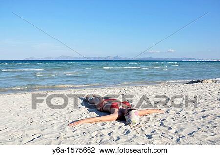 Mid adult woman sunbathing on beach, Alcudia, Mallorca, Spain, Europe View Large Photo Image Stock Image - Mid adult woman sunbathing on beach, Alcudia, Mallorca, Spain, Europe. Fotosearch