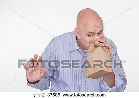 Stock Photography - Middle-age bald man blowing into a paper bag.. Fotosearch