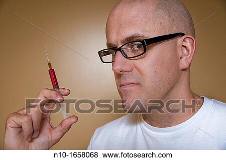 Middle-age bald man holding a syringe View Large Photo Image Stock Photo - Middle-age bald man holding a syringe. Fotosearch
