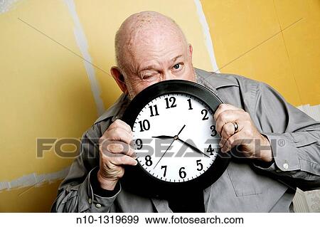 Middle-age balding man holding a clock View Large Photo Image Stock Photo - Middle-age balding man holding a clock. Fotosearch