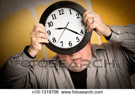 Middle-age balding man holding a clock View Large Photo Image Stock Photograph - Middle-age balding man holding a clock. Fotosearch
