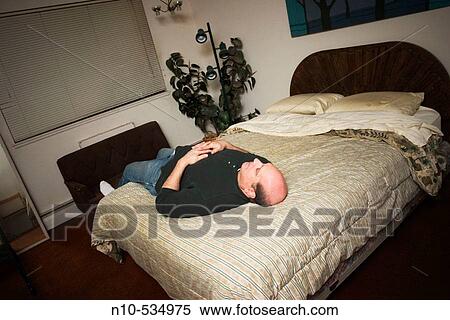 Middle-age balding man lying on his bed View Large Photo Image Stock Photography - Middle-age balding man lying on his bed. Fotosearch