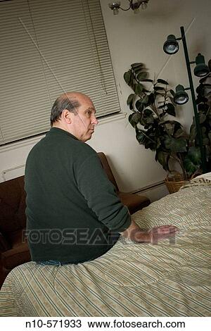 Middle-age balding man sitting on his bed View Large Photo Image Stock Image - Middle-age balding man sitting on his bed. Fotosearch