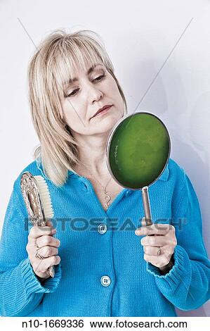 Middle-age blond woman holding a hairbrush and a hand mirror View Large Photo Image Stock Photograph - Middle-age blond woman holding a hairbrush and a hand mirror. Fotosearch