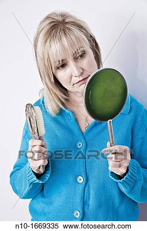 Middle-age blond woman holding a hairbrush and a hand mirror View Large Photo Image Stock Photography - Middle-age blond woman holding a hairbrush and a hand mirror. Fotosearch