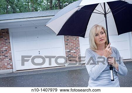 Stock Photo - Middle-age blond woman in the rain with an umbrella. Fotosearch
