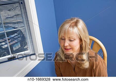 Middle-age blond woman sitting by a window View Large Photo Image Stock Photo - Middle-age blond woman sitting by a window. Fotosearch