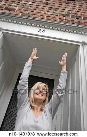 Middle-age blond woman standing by her front door View Large Photo Image Stock Photo - Middle-age blond woman standing by her front door. Fotosearch