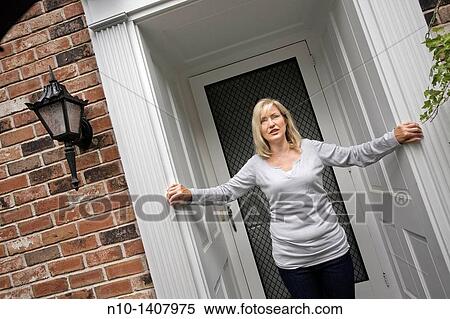 Middle-age blond woman standing by her front door View Large Photo Image Stock Photography - Middle-age blond woman standing by her front door. Fotosearch