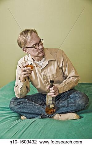 Middle-age man holding a bottle and a glass of liquor View Large Photo Image Stock Image - Middle-age man holding a bottle and a glass of liquor. Fotosearch