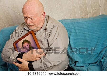 Stock Photo - Middle-age man holding a framed picture of a young girl. Fotosearch