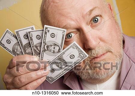 Stock Image - Middle-age man holding small copies of American money. Fotosearch