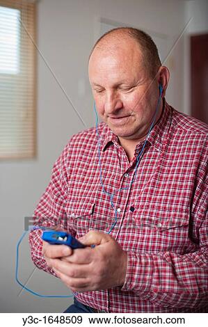 Middle age man in his 50s listening to music on iPhone View Large Photo Image Stock Photo - Middle age man in his 50s listening to music on iPhone. Fotosearch