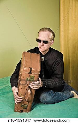 Middle-age man sitting on a bed with a suitcase View Large Photo Image Stock Photo - Middle-age man sitting on a bed with a suitcase. Fotosearch