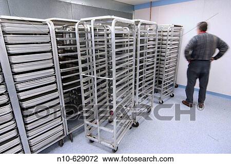 Middle age man standing near metal tray racks in a factory. View Large Photo Image Stock Image - Middle age man standing near metal tray racks in a factory.. Fotosearch
