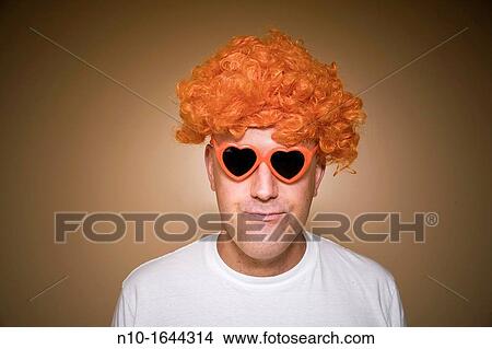 Middle-age man wearing an orange wig and heart-shaped sunglasses View Large Photo Image Picture - Middle-age man wearing an orange wig and heart-shaped sunglasses. Fotosearch
