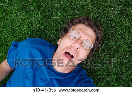 Middle age man, wearing glasses and eyes closed, lying on the grass in a park. View Large Photo Image Stock Photography - Middle age man, wearing glasses and eyes closed, lying on the grass in a park.. Fotosearch