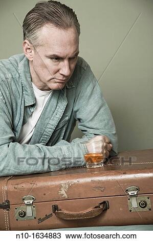 Middle-age man with a drink setting on a suitcase View Large Photo Image Stock Image - Middle-age man with a drink setting on a suitcase. Fotosearch