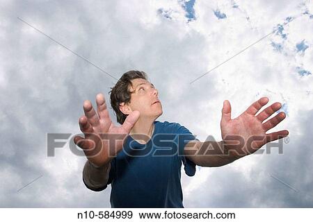 Middle-age man, with his arms outstretched, posing in front of a cloudy sky. View Large Photo Image Stock Photo - Middle-age man, with his arms outstretched, posing in front of a cloudy sky.. Fotosearch