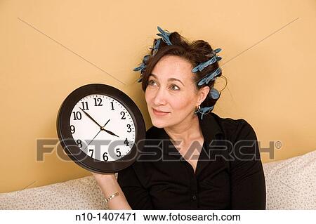 Middle-age woman in curlers, holding a wall clock View Large Photo Image Stock Image - Middle-age woman in curlers, holding a wall clock. Fotosearch