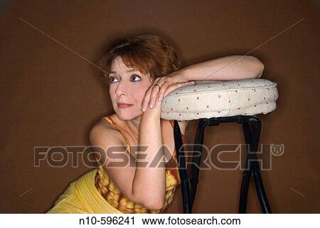 Middle-age woman resting her arms on a stool. View Large Photo Image Stock Image - Middle-age woman resting her arms on a stool.. Fotosearch