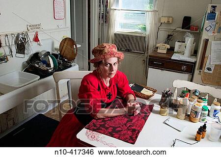 Middle age woman, wearing a red dress and hat, sitting at the table in her kitchen, thinking. View Large Photo Image Stock Photograph - Middle age woman, wearing a red dress and hat, sitting at the table in her kitchen, thinking.. Fotosearch