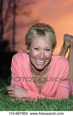 Middle aged blond woman dressed up playfully on the grass to enjoy the sunset or sunrise View Large Photo Image Stock Photography - Middle aged blond woman dressed up playfully on the grass to enjoy the sunset or sunrise. Fotosearch