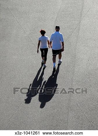 Middle-aged couple walking for exercise in the early morning sun View Large Photo Image Stock Image - Middle-aged couple walking for exercise in the early morning sun. Fotosearch
