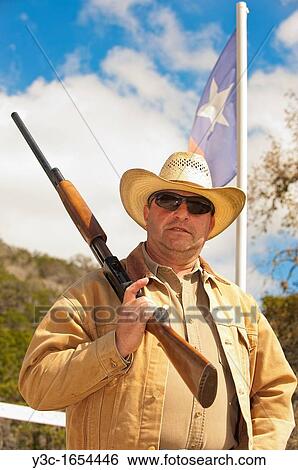Middle-aged cowboy with firearm in front of Texas flag View Large Photo Image Stock Photograph - Middle-aged cowboy with firearm in front of Texas flag. Fotosearch