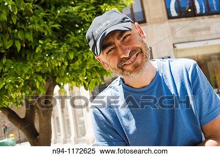 Middle-aged man with a beard and cap, in the center of the city, looking at the photographer tilted. View Large Photo Image Stock Photography - Middle-aged man with a beard and cap, in the center of the city, looking at the photographer tilted.. Fotosearch