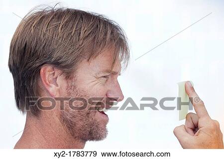 Middle aged man with beard growth looking at yellow note stuck to his finger View Large Photo Image Stock Photo - Middle aged man with beard growth looking at yellow note stuck to his finger. Fotosearch