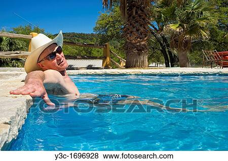 Middle-aged man with cowboy hat and sun glasses refreshing and relaxing in a swimming pool View Large Photo Image Stock Photo - Middle-aged man with cowboy hat and sun glasses refreshing and relaxing in a swimming pool. Fotosearch