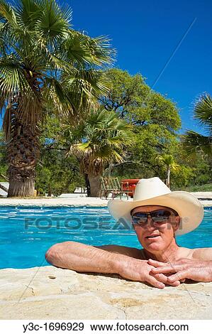 Middle-aged man with cowboy hat and sun glasses refreshing and relaxing in a swimming pool View Large Photo Image Stock Photo - Middle-aged man with cowboy hat and sun glasses refreshing and relaxing in a swimming pool. Fotosearch