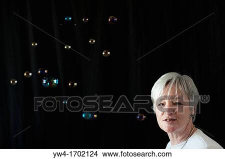 Middle aged woman and bubbles against black background View Large Photo Image Picture - Middle aged woman and bubbles against black background. Fotosearch