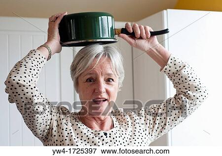Middle aged woman holding saucepan above her head View Large Photo Image Stock Photo - Middle aged woman holding saucepan above her head. Fotosearch