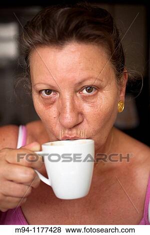 Middle aged woman looking at camera and drinking coffee View Large Photo Image Stock Photo - Middle aged woman looking at camera and drinking coffee. Fotosearch