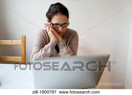 Stock Photo - Middle-aged woman reading on a laptop. Fotosearch