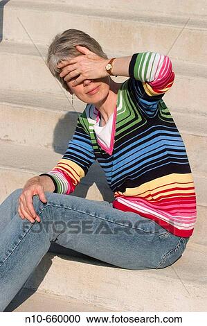 Middle-aged woman, sitting on concrete steps, covering her eyes with her hand. View Large Photo Image Stock Image - Middle-aged woman, sitting on concrete steps, covering her eyes with her hand.. Fotosearch