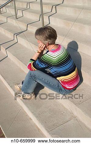 Stock Photo - Middle-aged woman sitting on concrete steps.. Fotosearch
