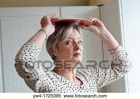 Middle aged woman with a plate on top of her head View Large Photo Image Stock Photography - Middle aged woman with a plate on top of her head. Fotosearch