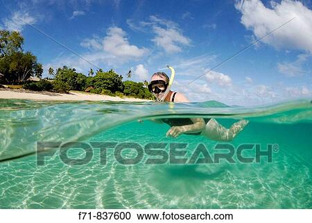 Stock Image - Middle aged women in one piece swim suit snorkelling over sandy on tropical beach. Ha`apai Group, Tonga. South Pacific Ocean.. Fotosearch