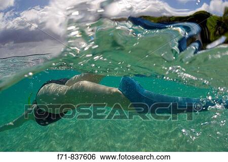 Stock Photograph - Middle aged women in one piece swim suit snorkelling over sandy on tropical beach. Ha`apai Group, Tonga. South Pacific Ocean.. Fotosearch