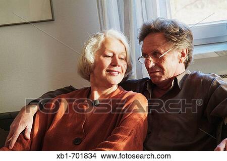 Middleaged couple is sitting on a couch View Large Photo Image Picture - Middleaged couple is sitting on a couch. Fotosearch