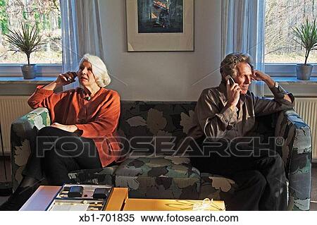Middleaged couple is sitting on a couch using their cellphones View Large Photo Image Stock Photography - Middleaged couple is sitting on a couch using their cellphones. Fotosearch